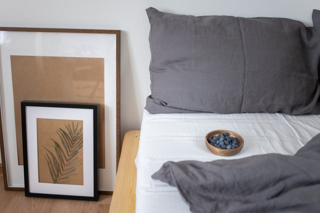 A cozy bedroom scene featuring minimalist art and a wooden bowl of blueberries on the bed.